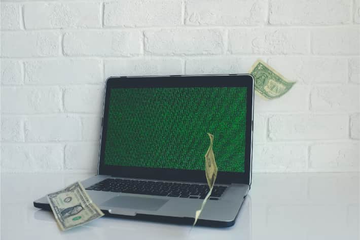 Equipo portátil hackeado con billetes de dólares cayendo