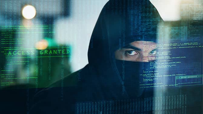 Comprender los diferentes tipos de malware puede ayudarlo a saber cómo protegerse mejor. La imagen muestra un hombre con una capucha puesta y la parte inferior de su rostro cubierto, parado detrás de una pantalla con las palabras “acceso otorgado” en ella.